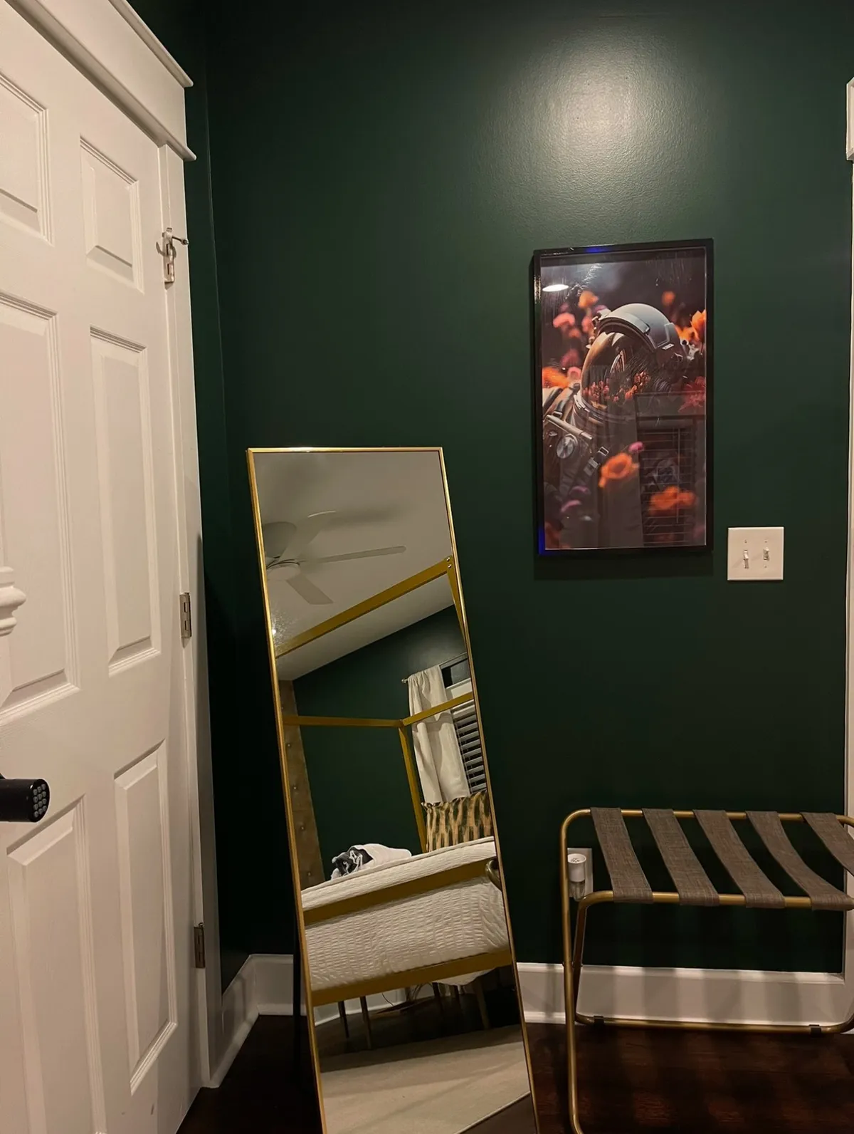 A stylishly decorated interior space featuring a golden-framed mirror, whimsical astronaut artwork, and a striped stool. The area exudes a boutique, creative vibe, suitable for moments of relaxation or for use as a functional nook for remote work or preparing for an outing.