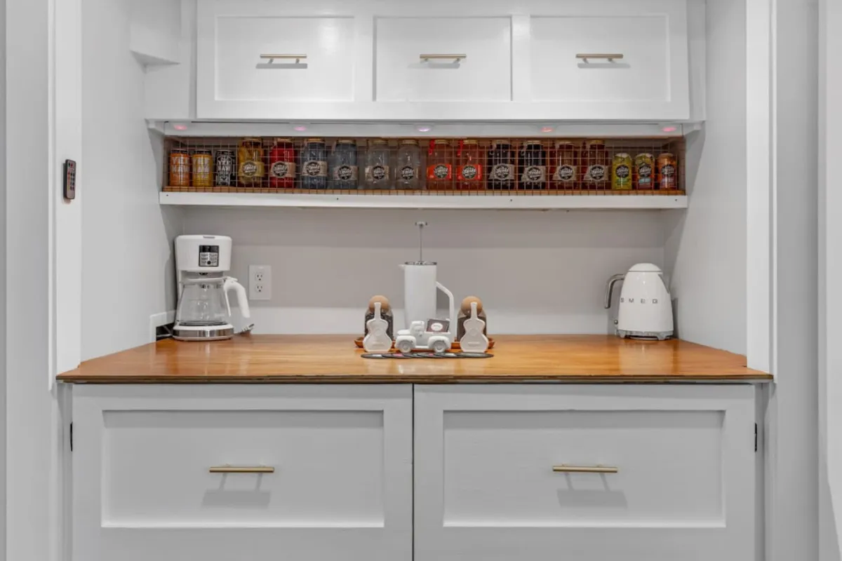 A close-up of a kitchen countertop showcasing a coffee maker, decorative jars, and a tray with coffee essentials like sugar and creamers. The area feels warm and thoughtfully arranged, highlighting the home's dedicated coffee bar.