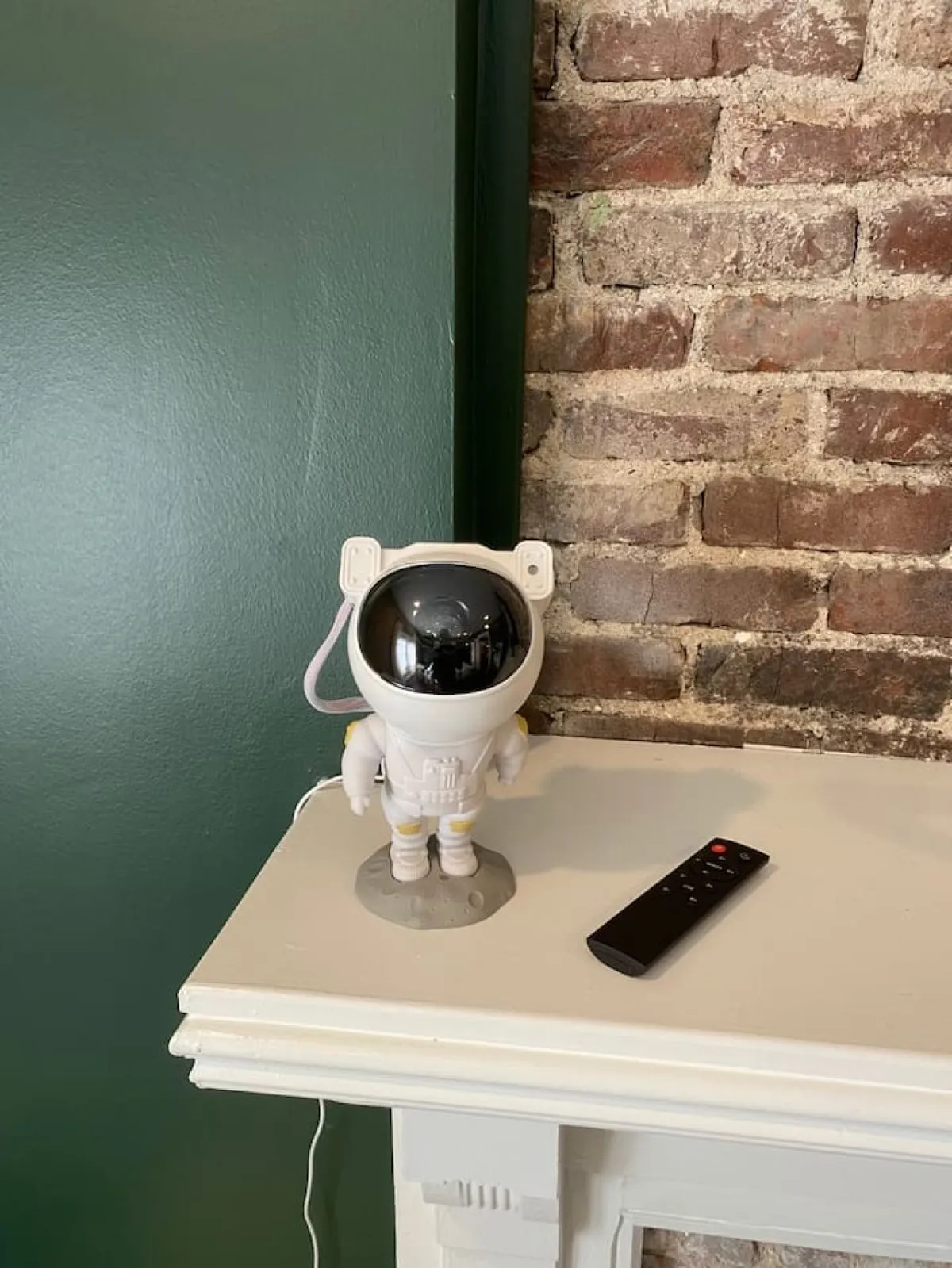 A whimsical living room corner featuring a conversation-starting astronaut lamp, a remote control, and a bold brick wall. The setup invites guests to settle in for a fun movie night or enjoy the playful, creative decor.