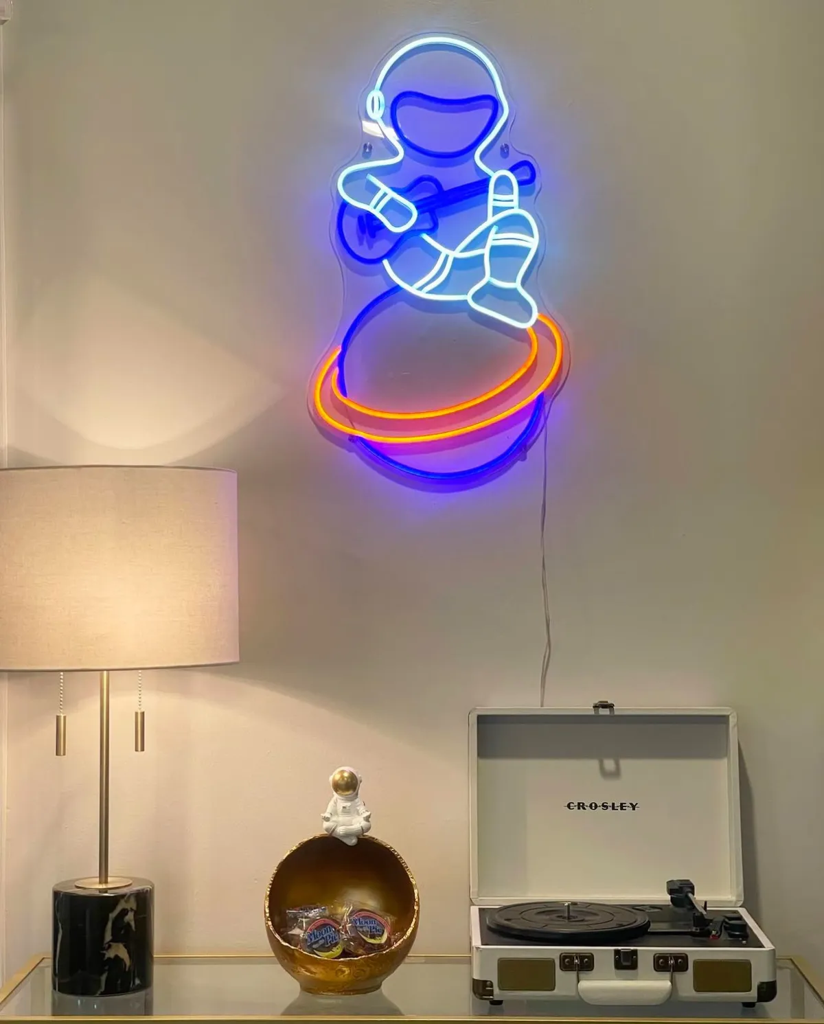 A cozy corner featuring a neon astronaut light, a record player, and inviting decorative accents. The ambiance is whimsical and uniquely Nashville, blending music culture with creative decor. This is a space for relaxing, listening to records, or entertaining guests after a night in town.