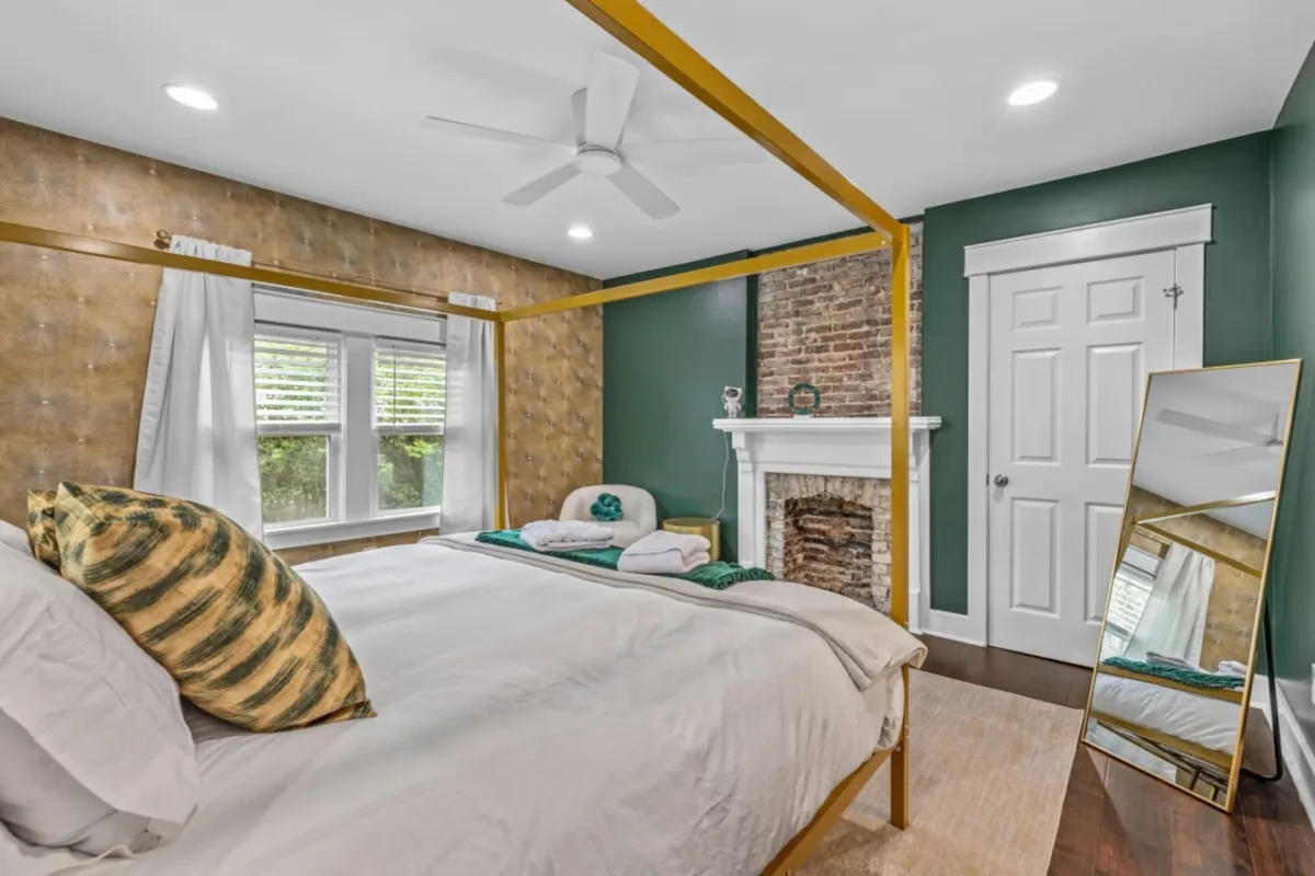 An intimate bedroom scene with a dreamy canopy bed positioned near a fireplace, softened by natural light filtering through the windows. The space is warm and inviting, encouraging couples to relax and enjoy quiet moments together.